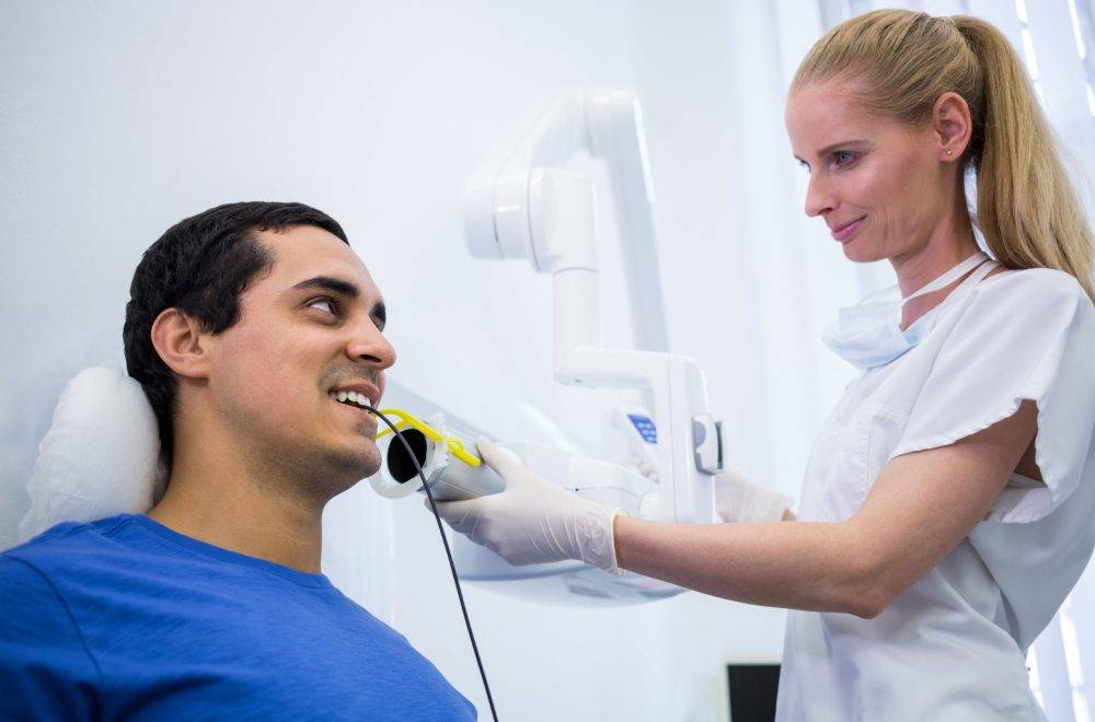 Dentist taking a male patients tooth x-ray in clinic